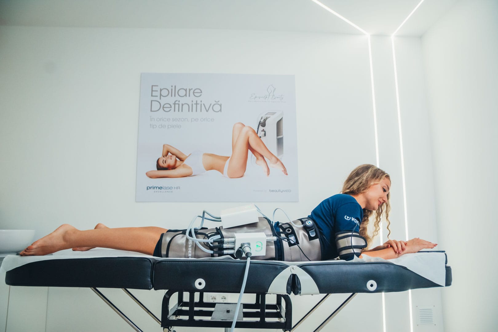 Femeie pe masa de tratament pentru tonifiere musculara prin electrostimulare